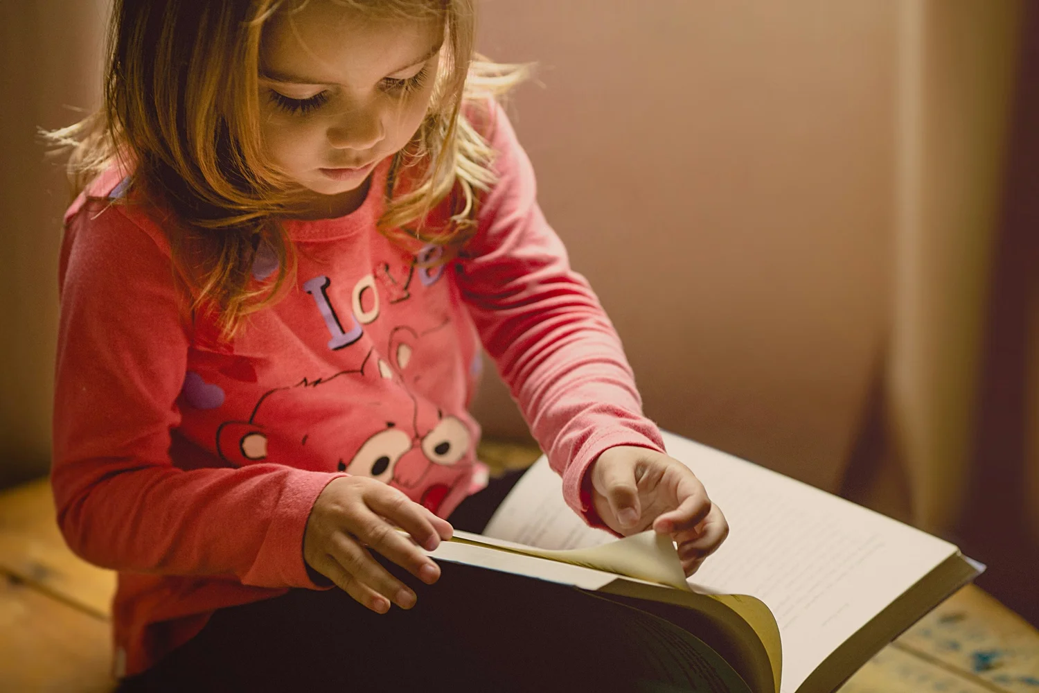A young girl turning the pages of a large bilingual children's book